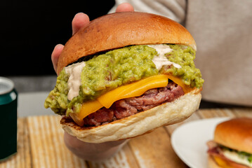 A delicious double cheddar beef patty with lots of guacamole and mayonnaise on top of the meat on a...