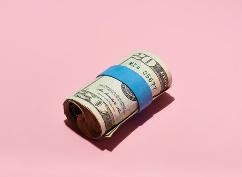 Roll of $20 USA Bills on Pink Background  
