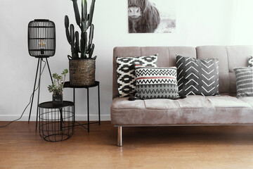 couch with pillows with black side tables and rattan floor lamp