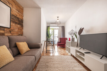 Salón decorado con paredes de madera sin barnizar en apartamento de alquiler a corto plazo con...