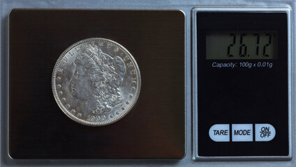 US Morgan silver dollar being weighed on digital scale - obrazy, fototapety, plakaty
