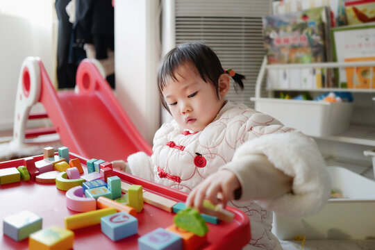 Asian baby builds blocks alone