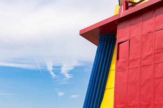 a colorful red wall next to a blue sky