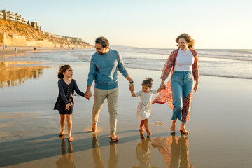 Mom, dad and girls walking on beach