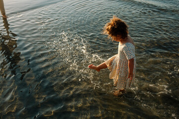 Young girl in dress wading in ocean 