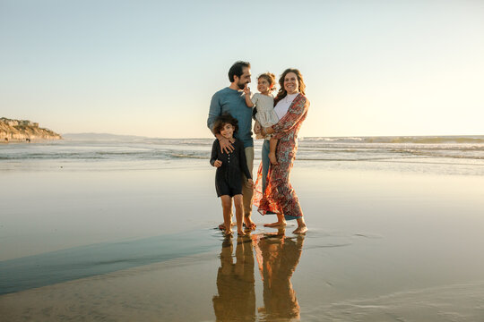 Happy family with two girls on beach at sunset