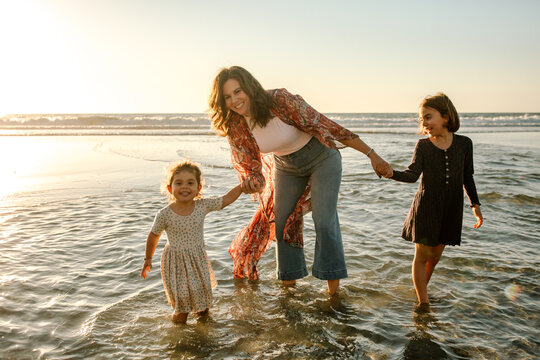 Mom and girls wading in ocean at sunset