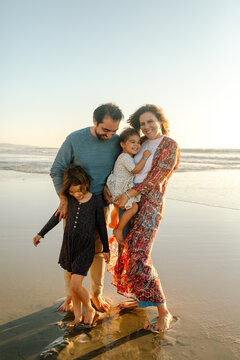Mom, dad and daughters on beach at sunset