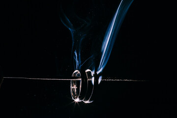 wedding rings with sparklers on a black background in smoke
