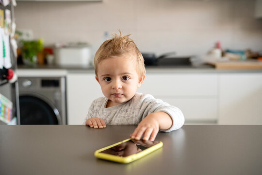 Toddler with smartphone looking at camera