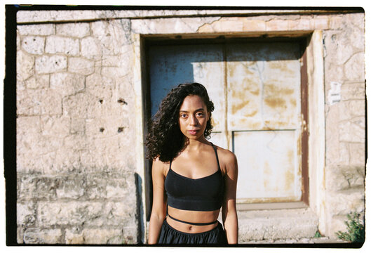 Fit woman in black outfit standing near old building