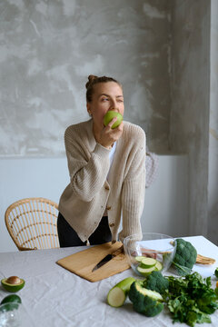 a woman biting a sour apple and wincing