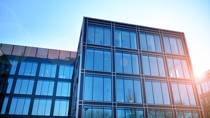 Minimalist glass facade, steel framework holding the large transparent panels. Contemporary commercial architecture, vertical converging geometric lines. Blue sky reflection in the glass panels