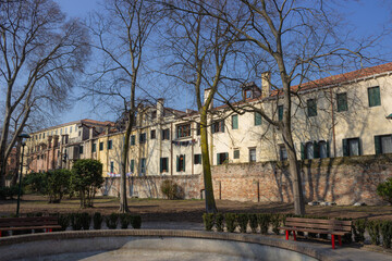 Fototapeta na wymiar Green area in the center of Venice. Popular buildings behind the trees.