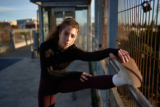 Flexible sportswoman stretching legs in city