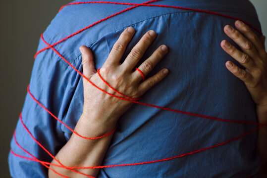 Elderly couple hugs and is tied with a red thread.
