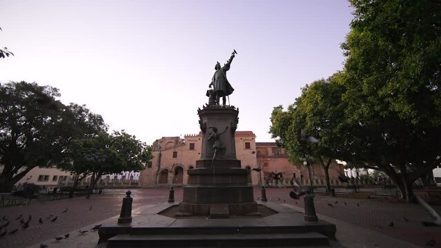 Monument to Christopher Columbus in Columbus Park, Colonial Zone. Slow motion of pigeons fly to camera in the foreground. Santo Domingo, Dominican Republic.