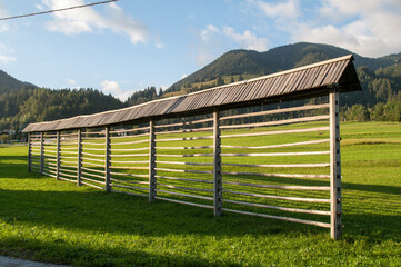 Wooden old stand for drying hay on a green grassy meadow in the mountains in Slovenia.