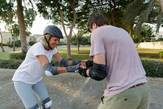 A man helps his mother to rollerblade