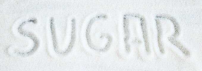 Granulated sugar scattered on a dark background banner. The inscription sugar