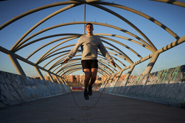 Sportsman skipping on bridge in evening