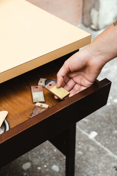 Hand holding an yellow ceramic sample on wooden drawer