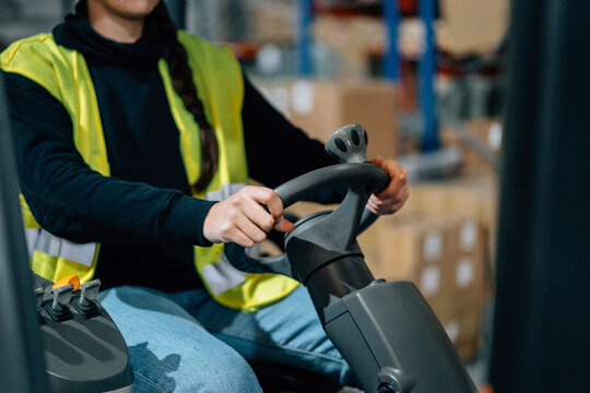 Anonymous storehouse worker riding electric forklift