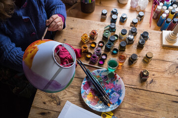 someone's hand painting a white lampshade