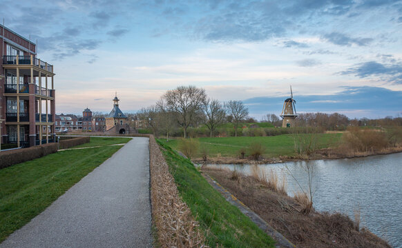 Pedestrian path along the historical fortifications in dutch city of Gorinchem with a view on windmill and an old city gate