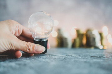 success and abundance concept, idea light bulb with stacks of different golden and silver coins representing a big amount of money