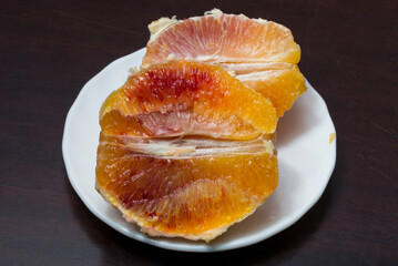 A dish with peeled and sliced oranges. Fresh bloody fruit.