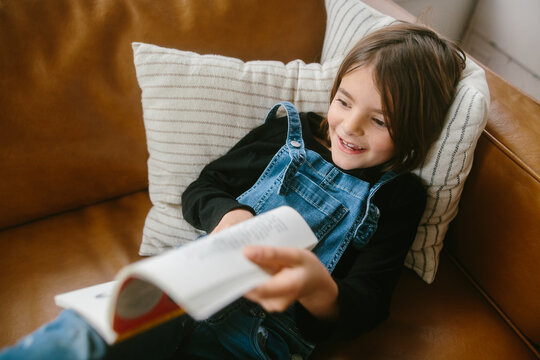 Young girl reading a book on couch