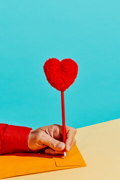 man about to write with a pen topped with a plush heart