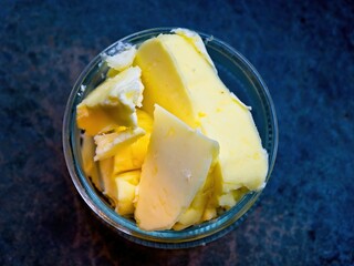 Slices of butter in a glass jar over the blue counter