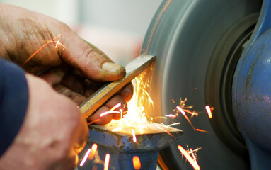 Factory worker sharpens his tool