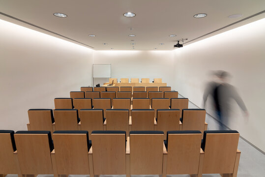 Person walking in meeting room with rows of chairs