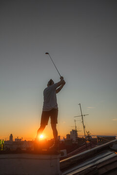 Silhouette of a man hitting a golf club on the roof