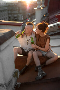 a girl and her boyfriend drink beer on the roof