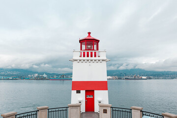 White lighthouse with red lines facing the sea