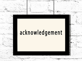 Black frame hanging on white brick wall with inscription acknowledgement