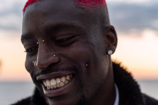 Cheerful black man with piercing on sea embankment