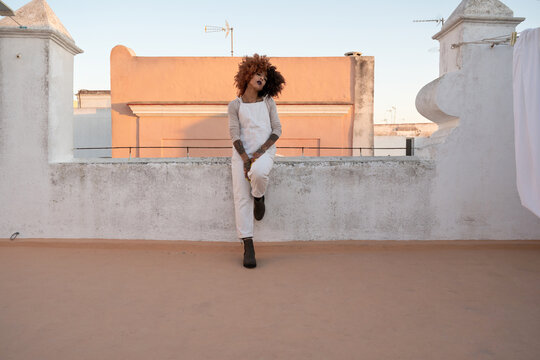 Provocative woman leaning on fence on rooftop
