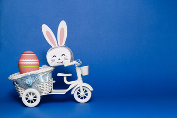 Easter bunny and easter egg on the toy bicycle with blue background.