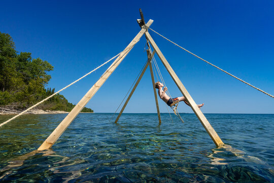 Boy Having Fun On a Sunny Lake Swing