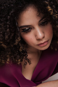 Model in maroon silk dress with glittery makeup on
