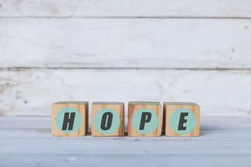hope concept written on wooden cubes or blocks, on white wood background.