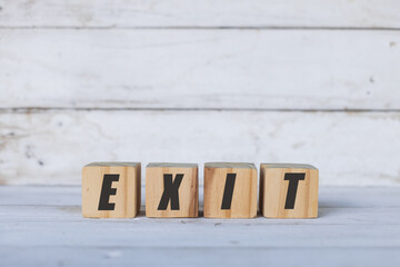 exit concept written on wooden cubes or blocks, on white wooden background.