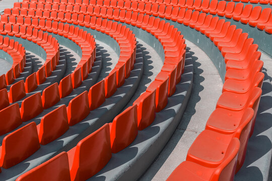 A row of red chairs in a curve in a sunny day