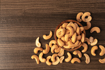 Cashew nut in wooden bowl on dark table.