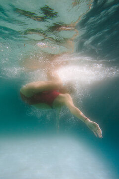 Woman in a red sports swimsuit swims in the pool